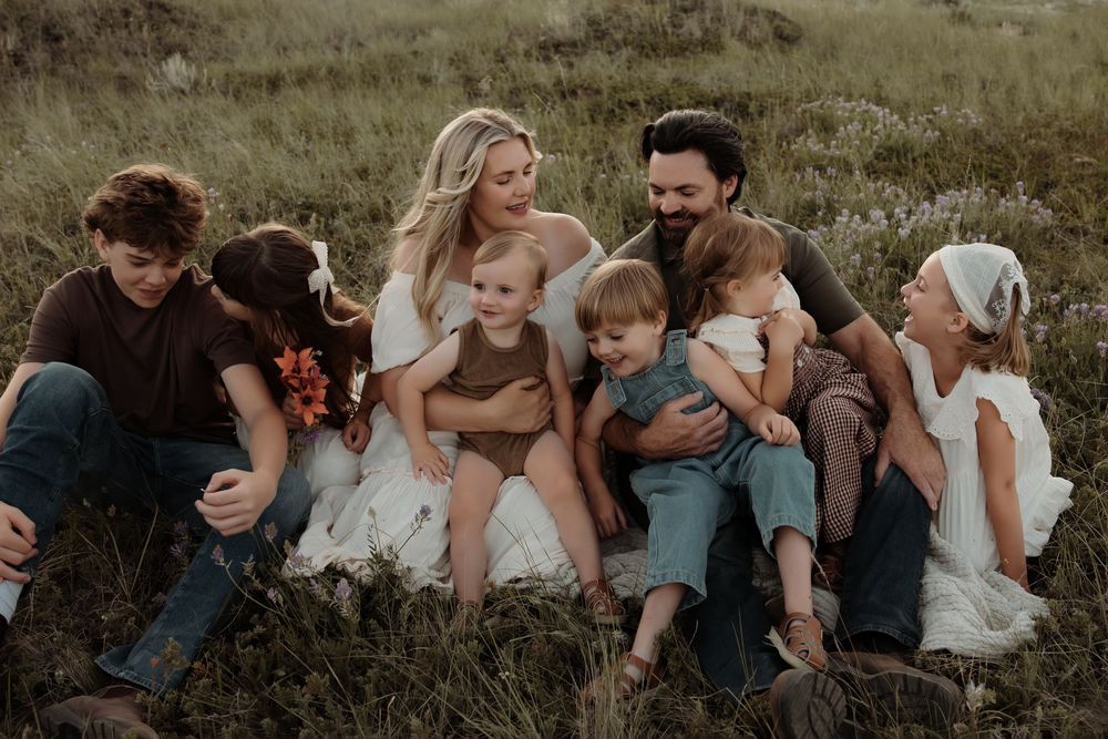 A family snuggle in close with laughter while a family photographer in Alberta captures the candid moment