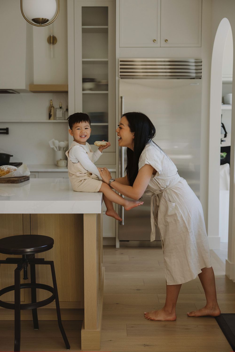 A mother smiles at her toddler son sitting on a kitchen island in her newly build home in calgary Albert during a photoshoot