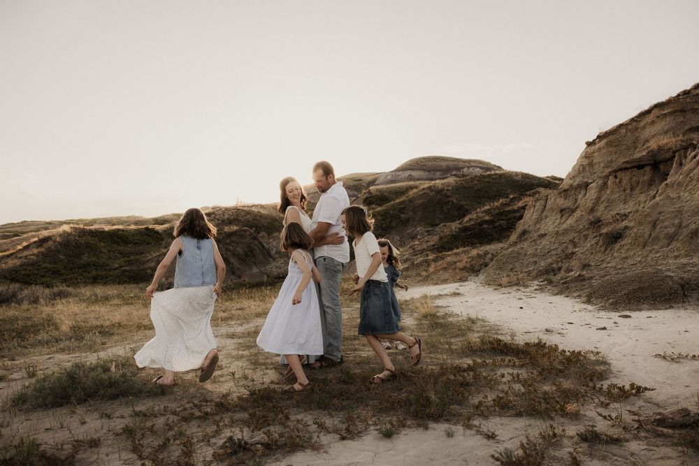 Family walking together in the badlands of alberta while alberta family photographer captures them playing