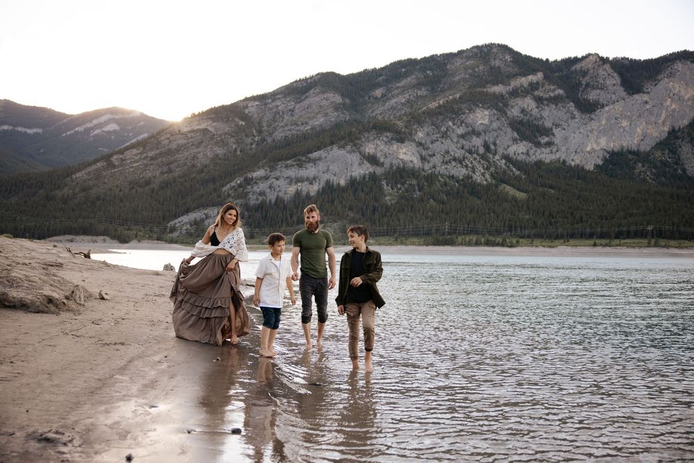 Family walking along Barrier lake shore looking at each other candidly during a golden hour photography shoot