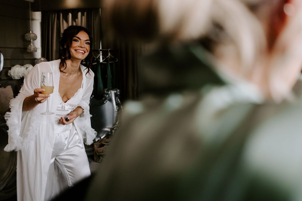 A joyful person in a white robe laughs while getting ready on their wedding day.