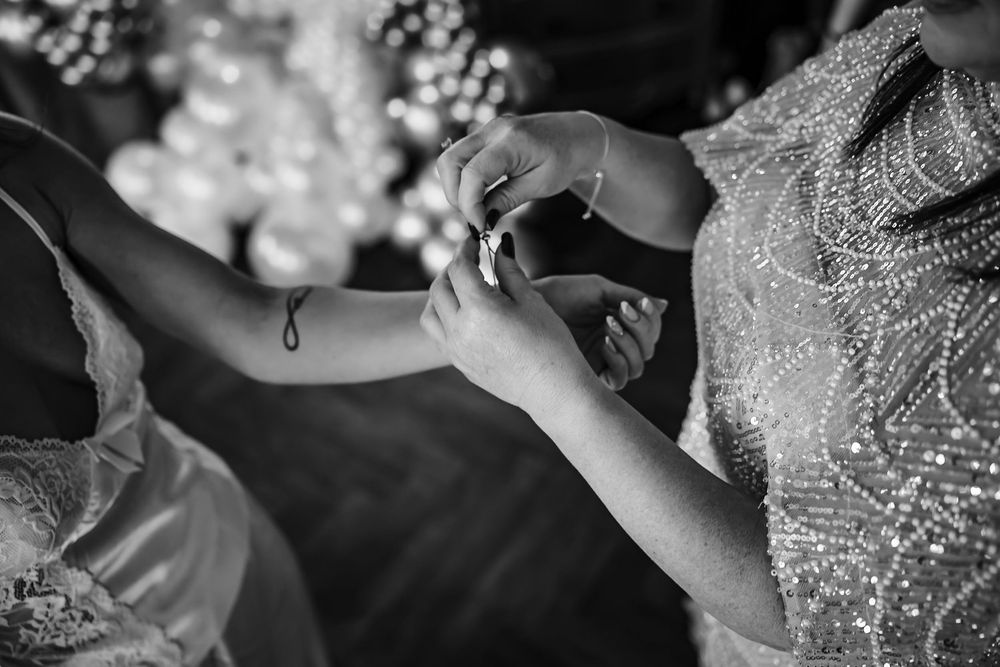 Black and white wedding photo showing hands with rings exchanging tender moments during a ceremony.