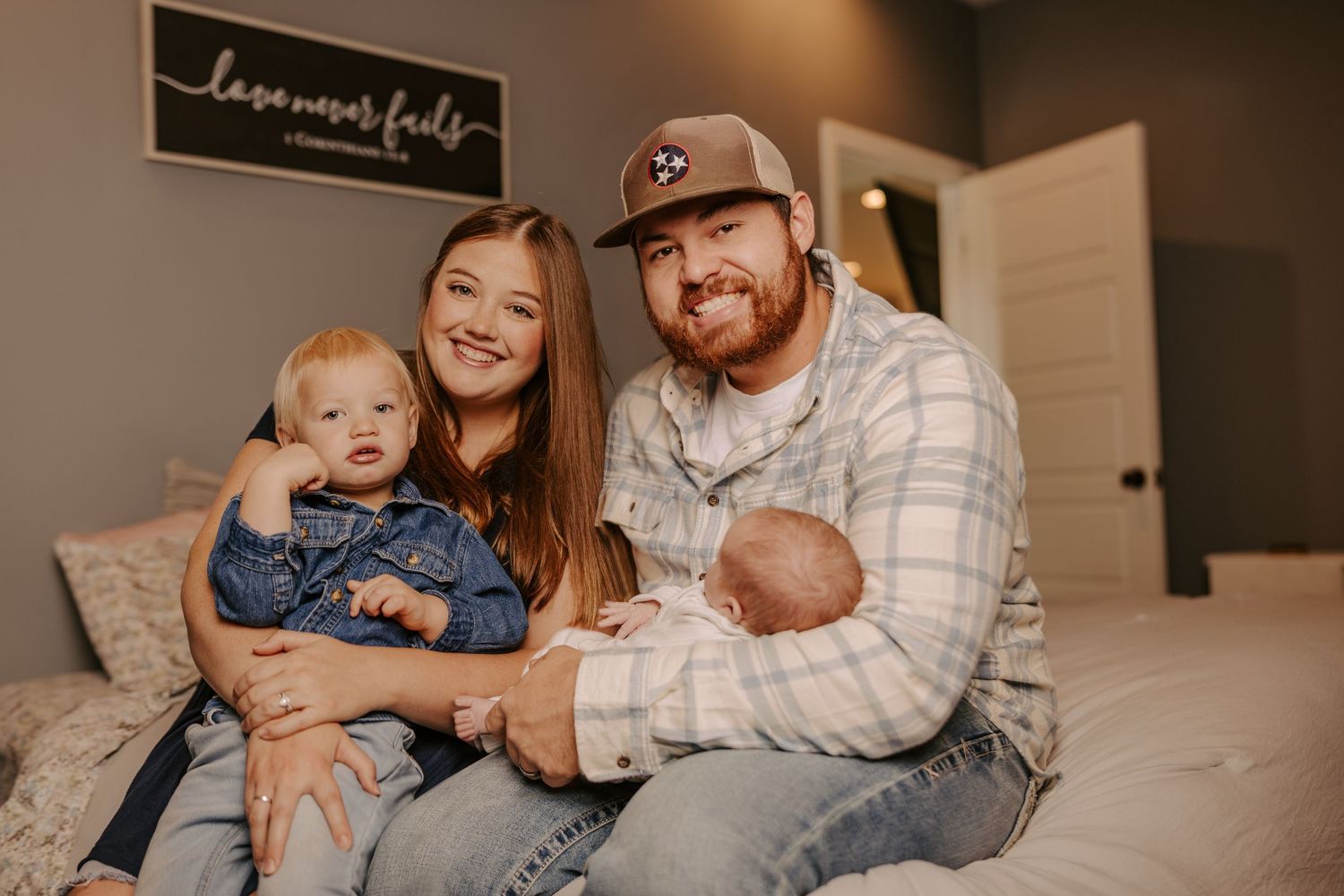 Cozy family lifestyle photo session on bed with warm lighting and casual attire.