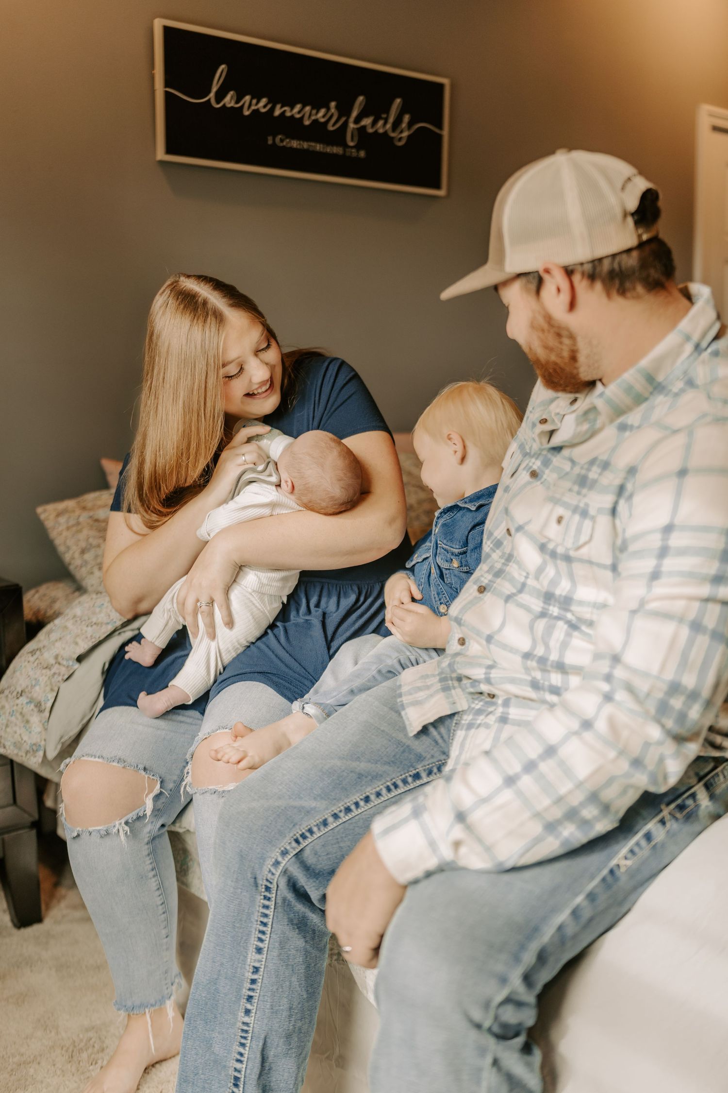 Intimate family moment captured on bed with casual denim and plaid clothing.