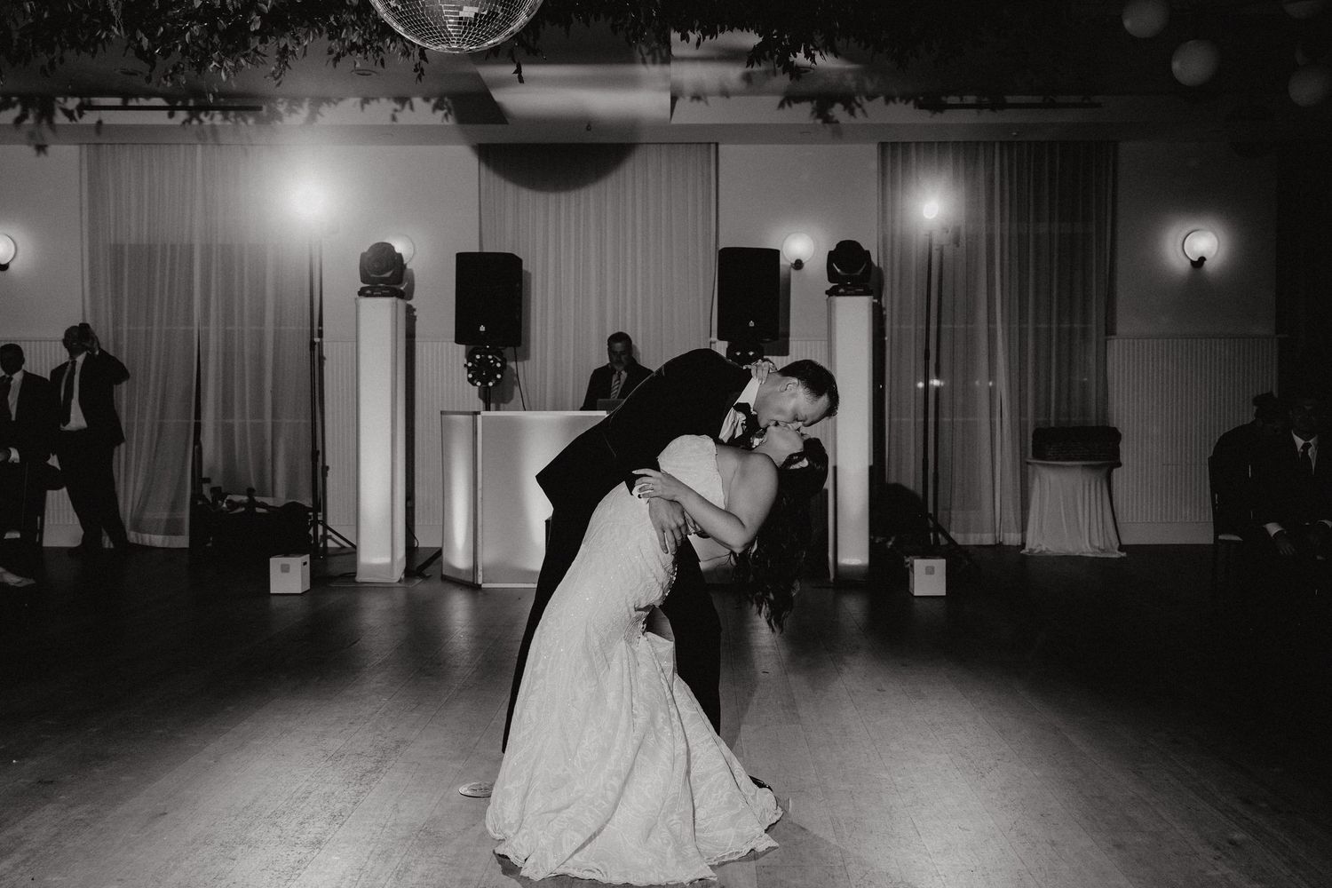 A couple shares a romantic dance dip on an elegant ballroom dance floor during their wedding celebration.