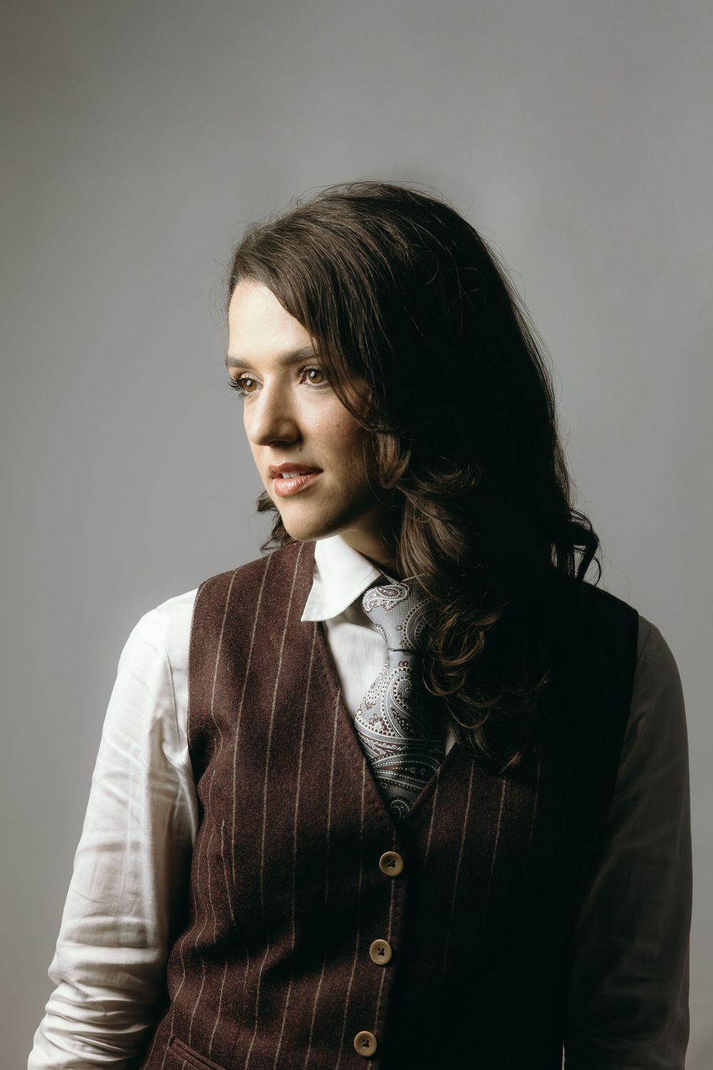 Artistic headshots featuring brown vest and white shirt in moody lighting against grey backdrop.