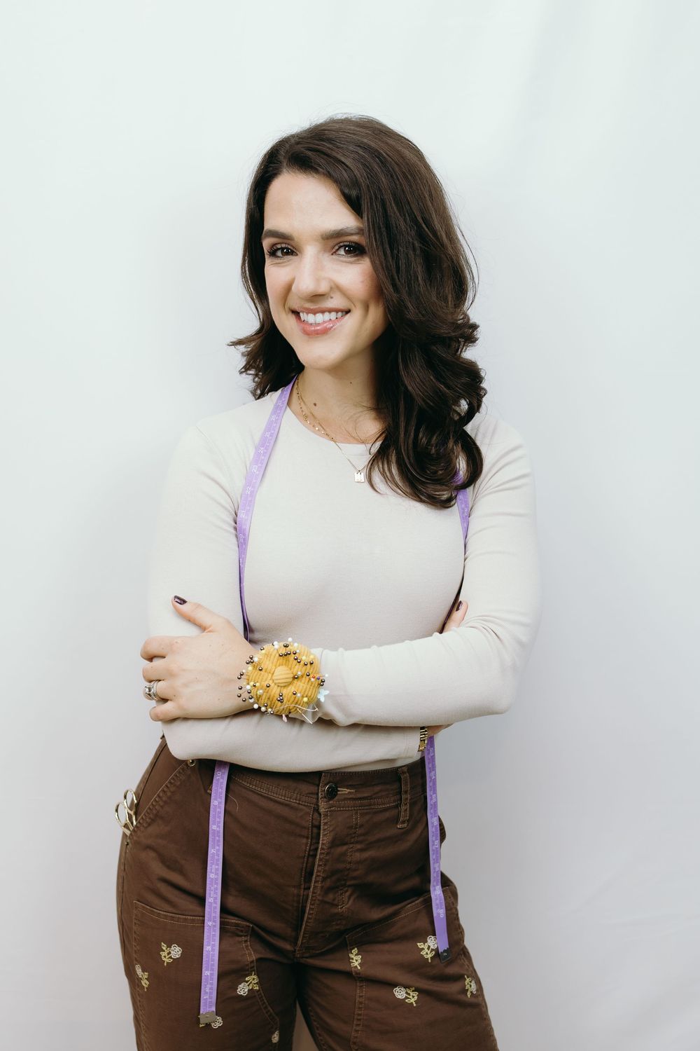 Casual portrait series with purple suspenders and brown pants against white background.