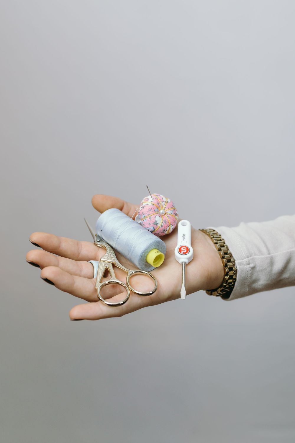 A sequence of hands holding small decorative items and rings against a light gray background.