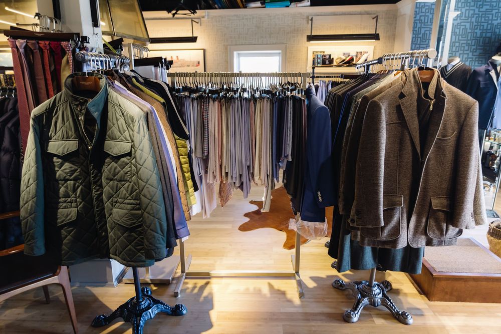 Interior view of a modern clothing retail store with racks of garments and bright lighting.