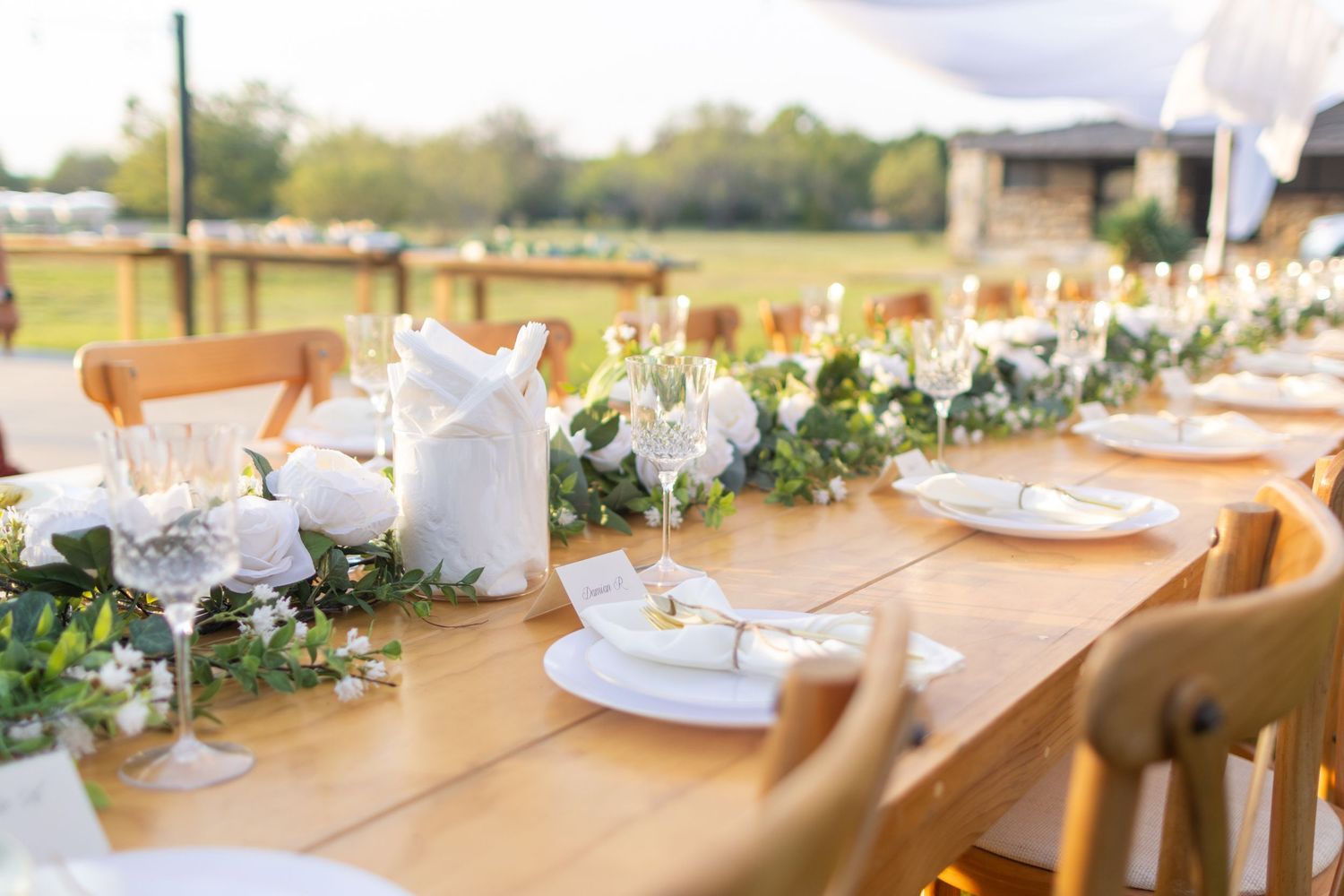 Elegant wedding reception table settings with white linens, floral centerpieces and natural decor in backyard wedding venue greenville texas
