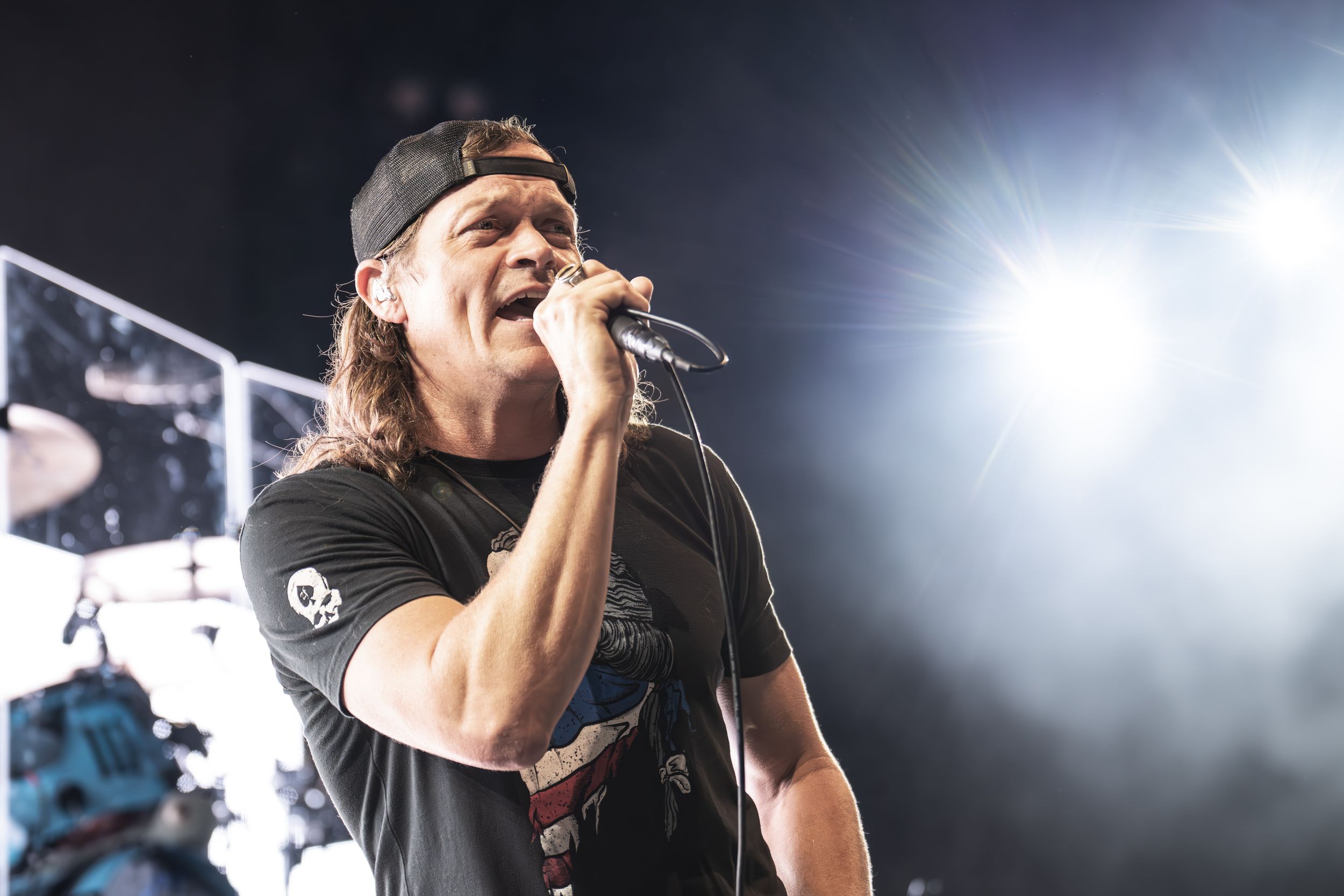 A performer sings passionately on stage with bright spotlights illuminating the dramatic scene during a live concert.