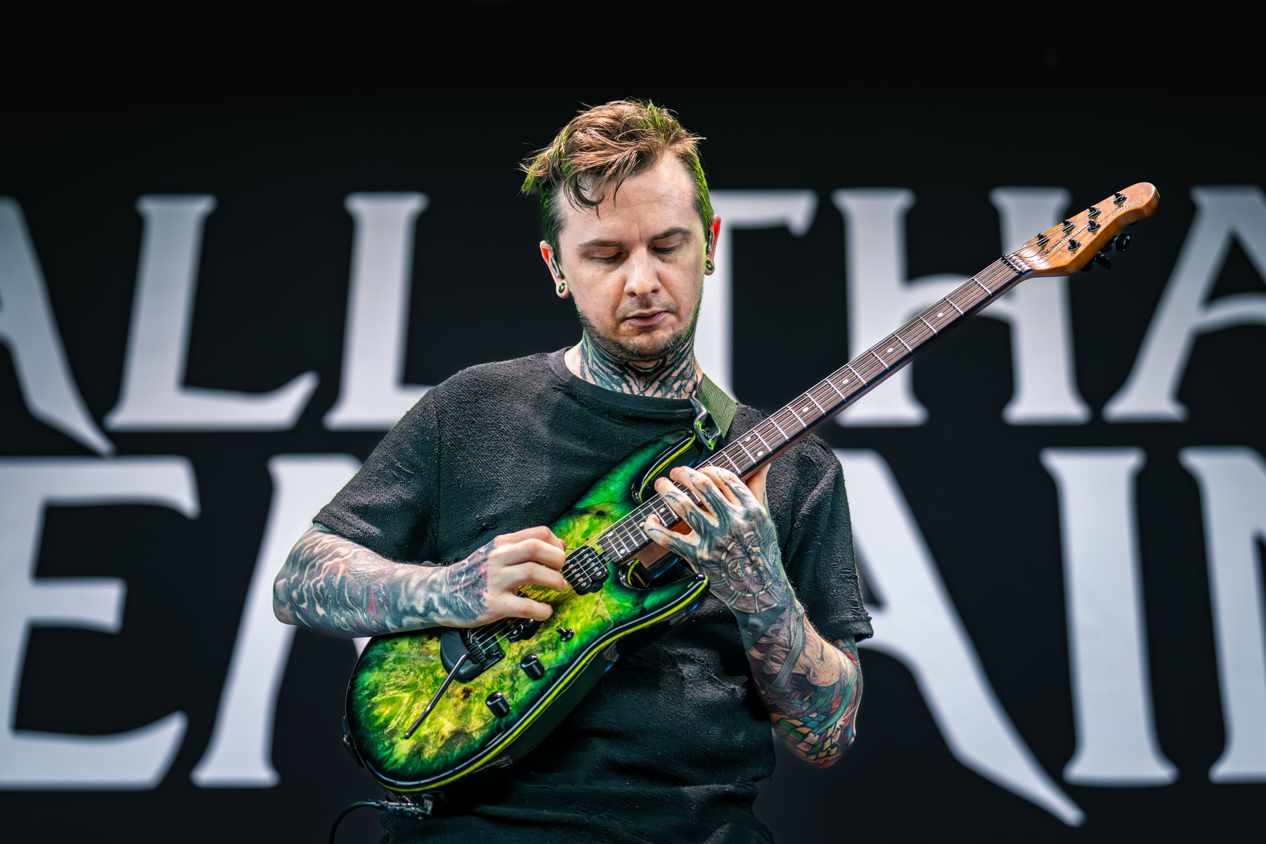A musician plays bass guitar on stage with dramatic lighting and a black background.