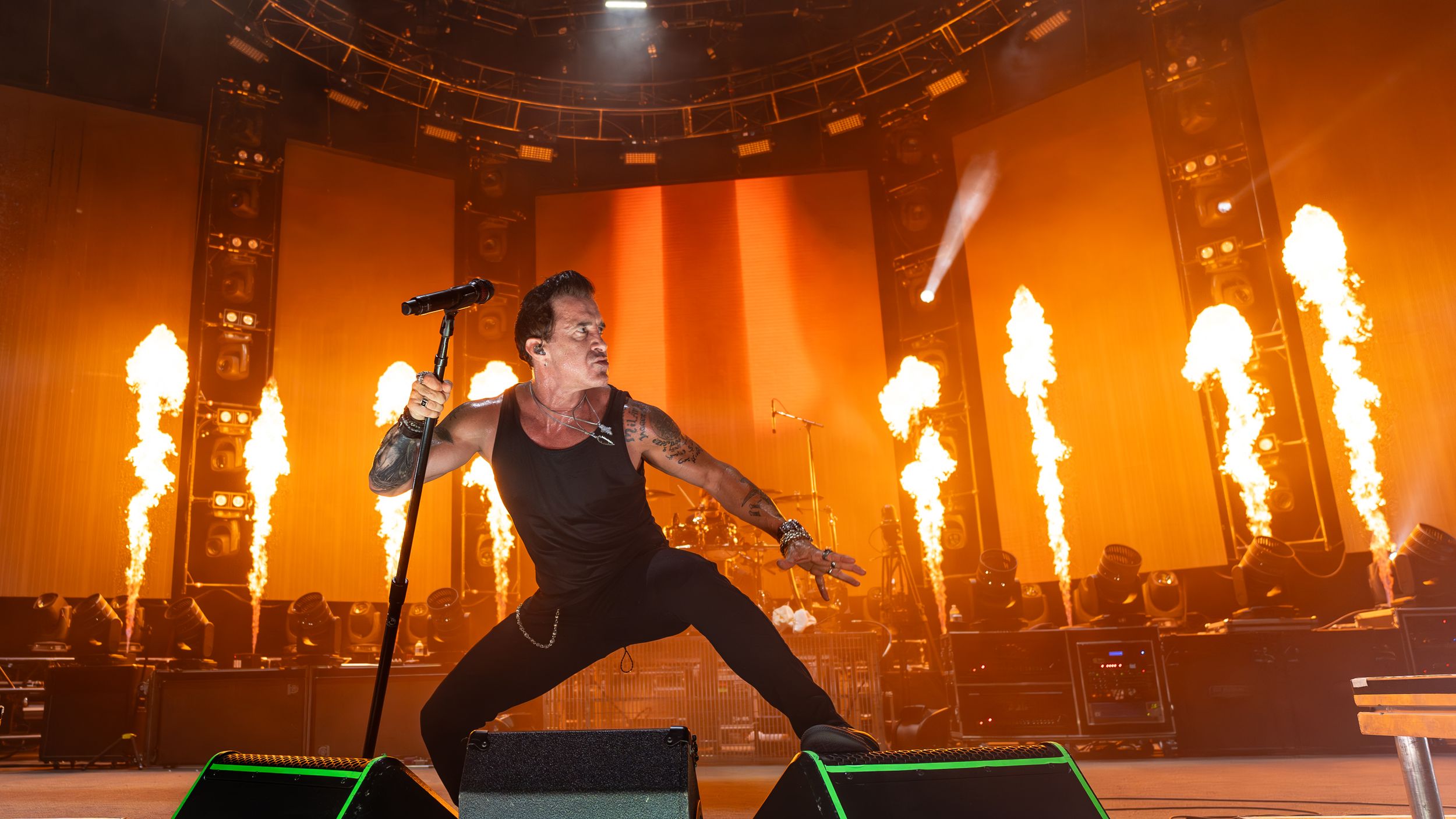 Concert stage performance with dramatic fire effects and pyrotechnics creating an intense orange atmosphere.