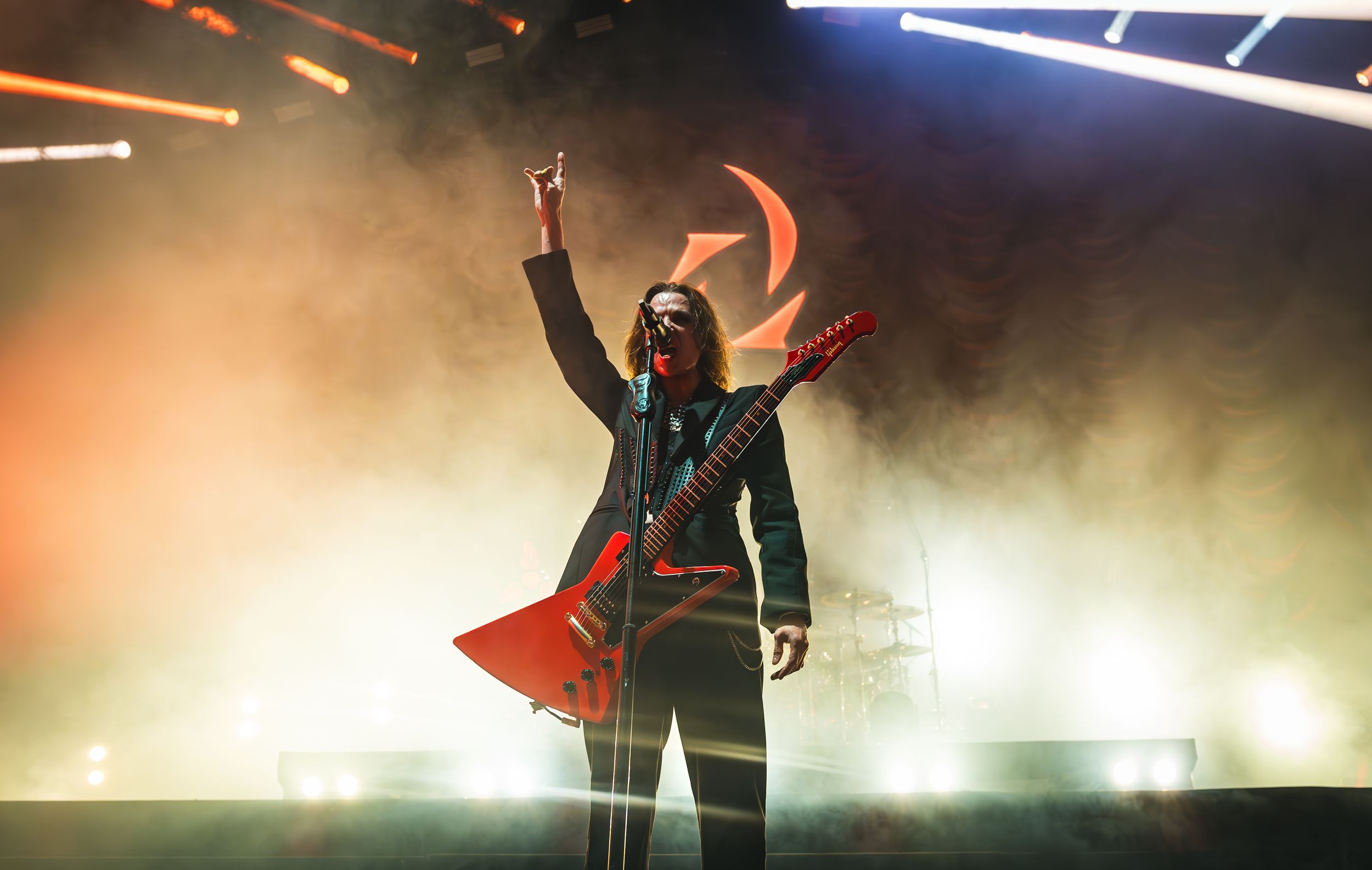 Concert performer silhouetted against dramatic stage lighting with fog effects during an energetic live performance.