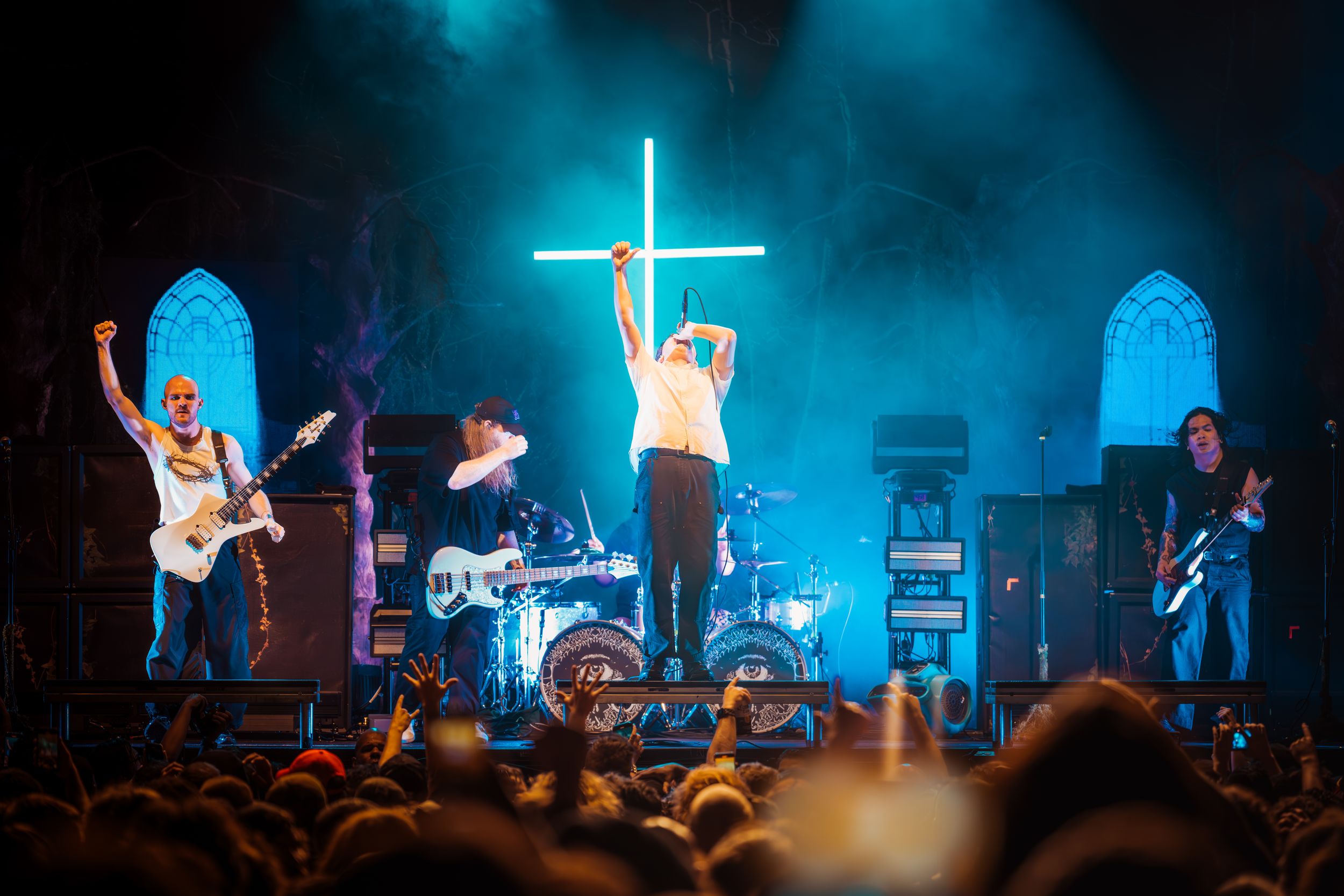 Concert performers on stage bathed in dramatic blue lighting create an energetic atmosphere during a live show.