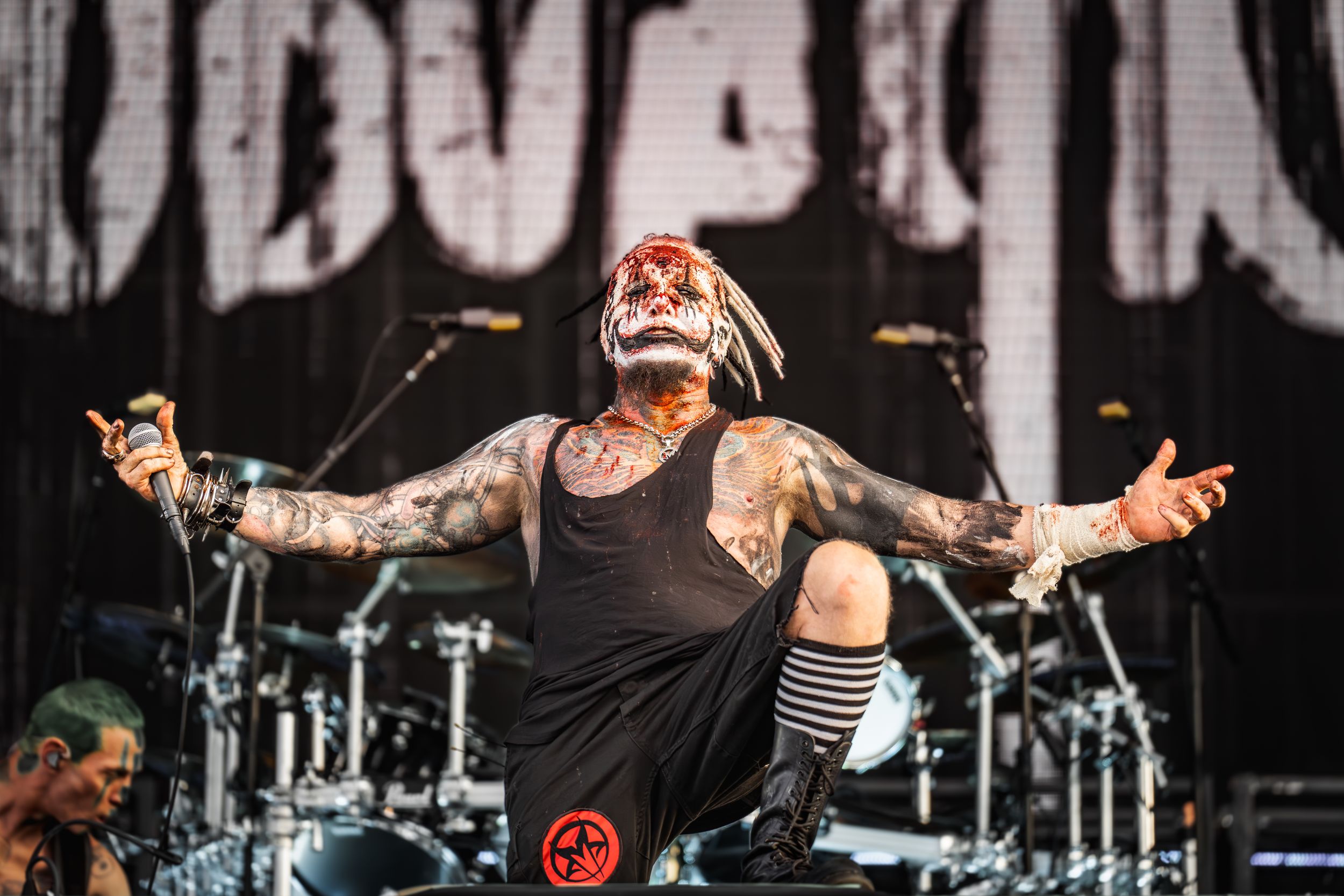 Heavy metal band performs energetically on stage with dramatic lighting and theatrical makeup during a live concert.