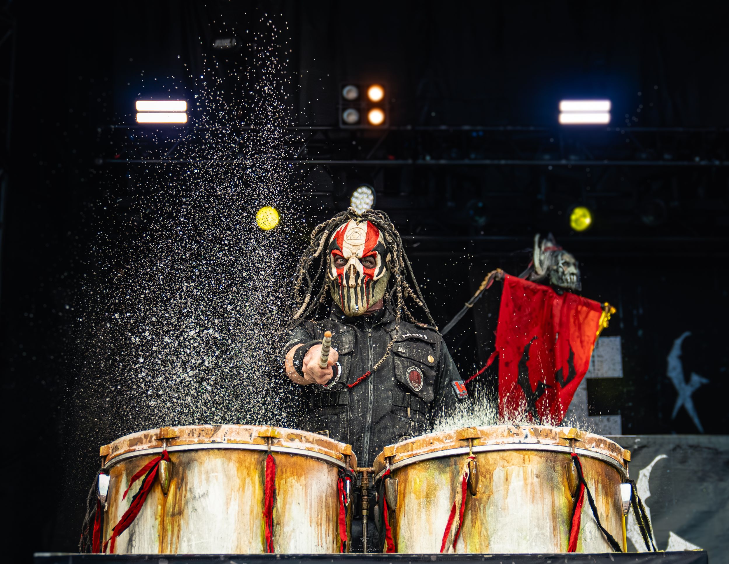 A dark stage performance features illuminated pumpkins and red fabric creating an eerie Halloween atmosphere.