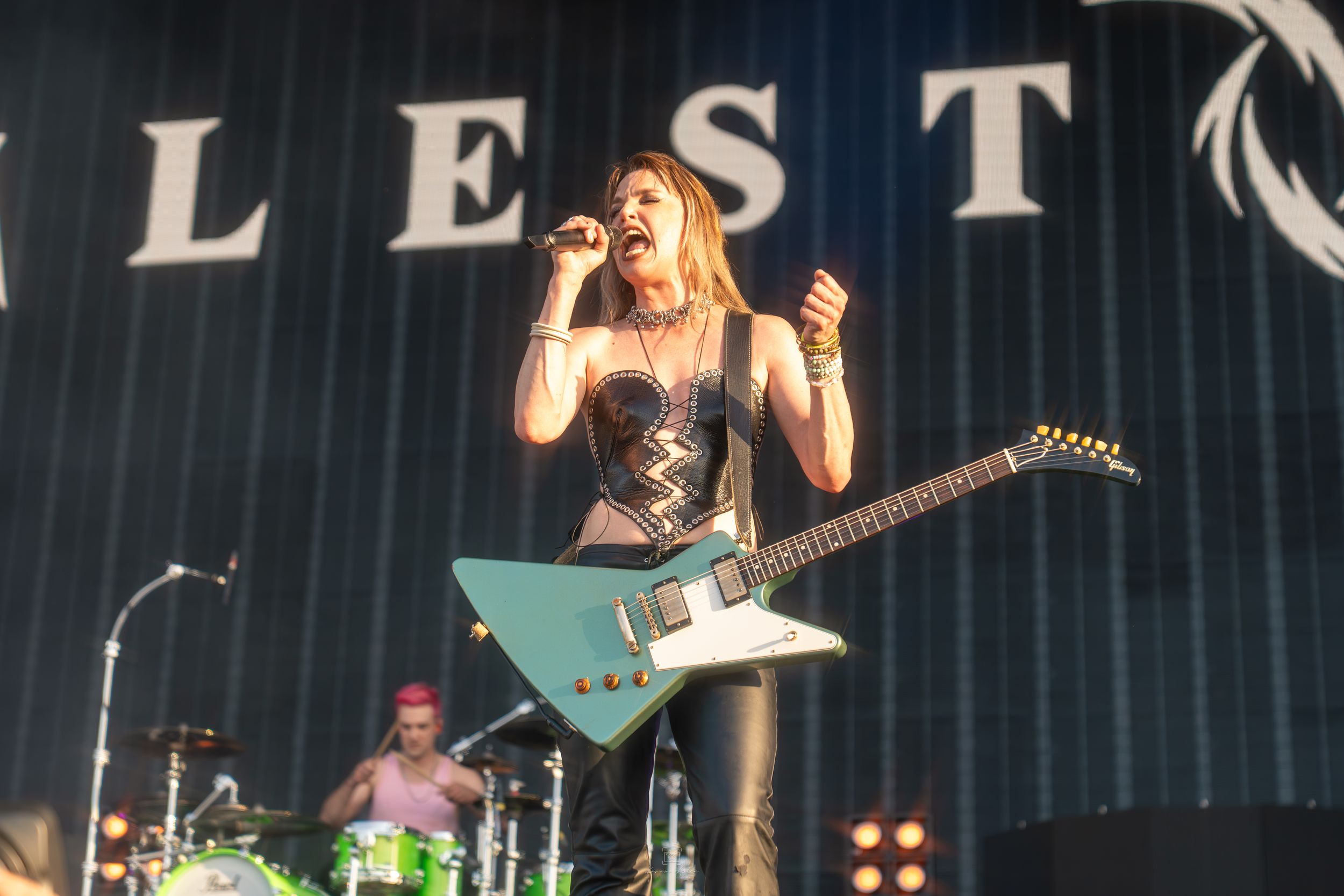 Rock band performs energetically on stage with dramatic lighting and smoke effects during live concert performance.