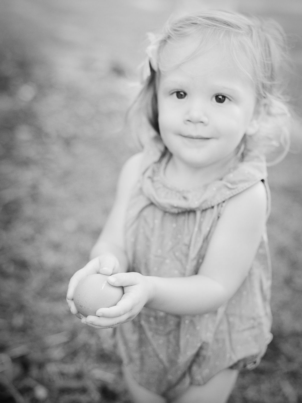 Young child in a flowy dress looking up with wonder in black and white portrait.