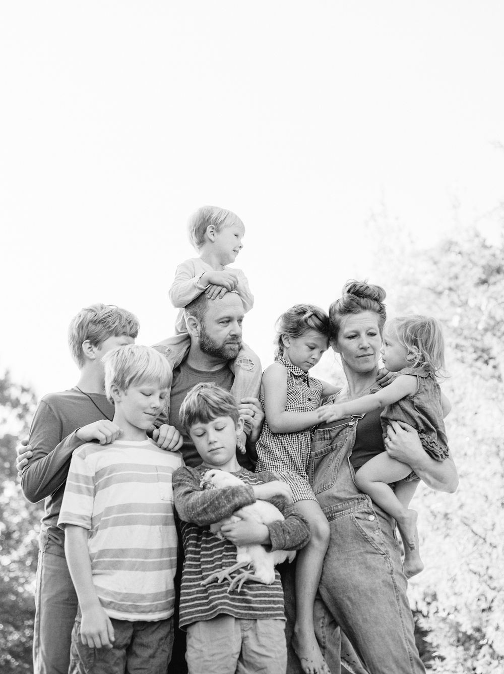 A black and white photograph shows a group embracing while gathered together outdoors.