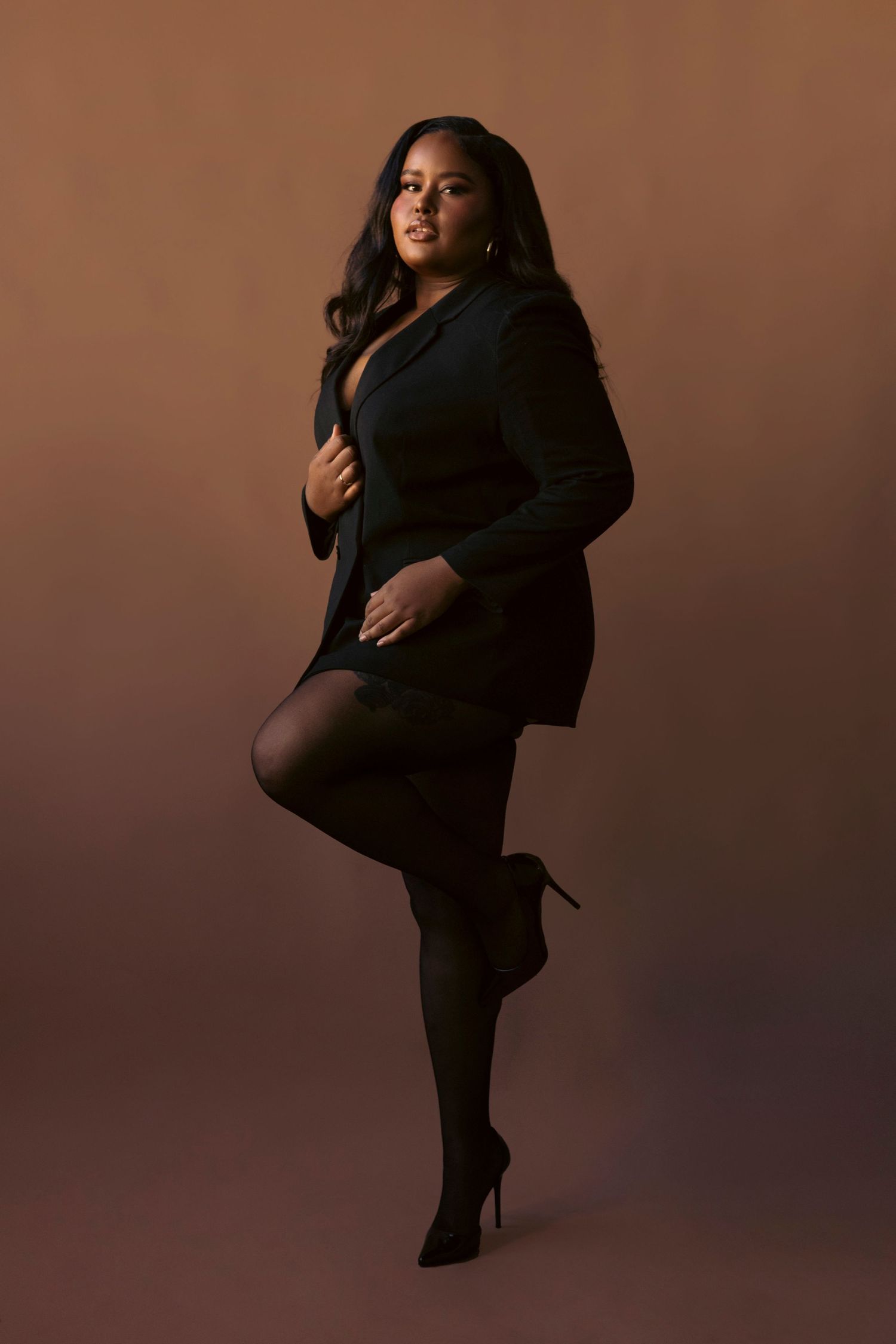 Figure in black outfit performs dramatic dance poses against brown backdrop in artistic photo series.