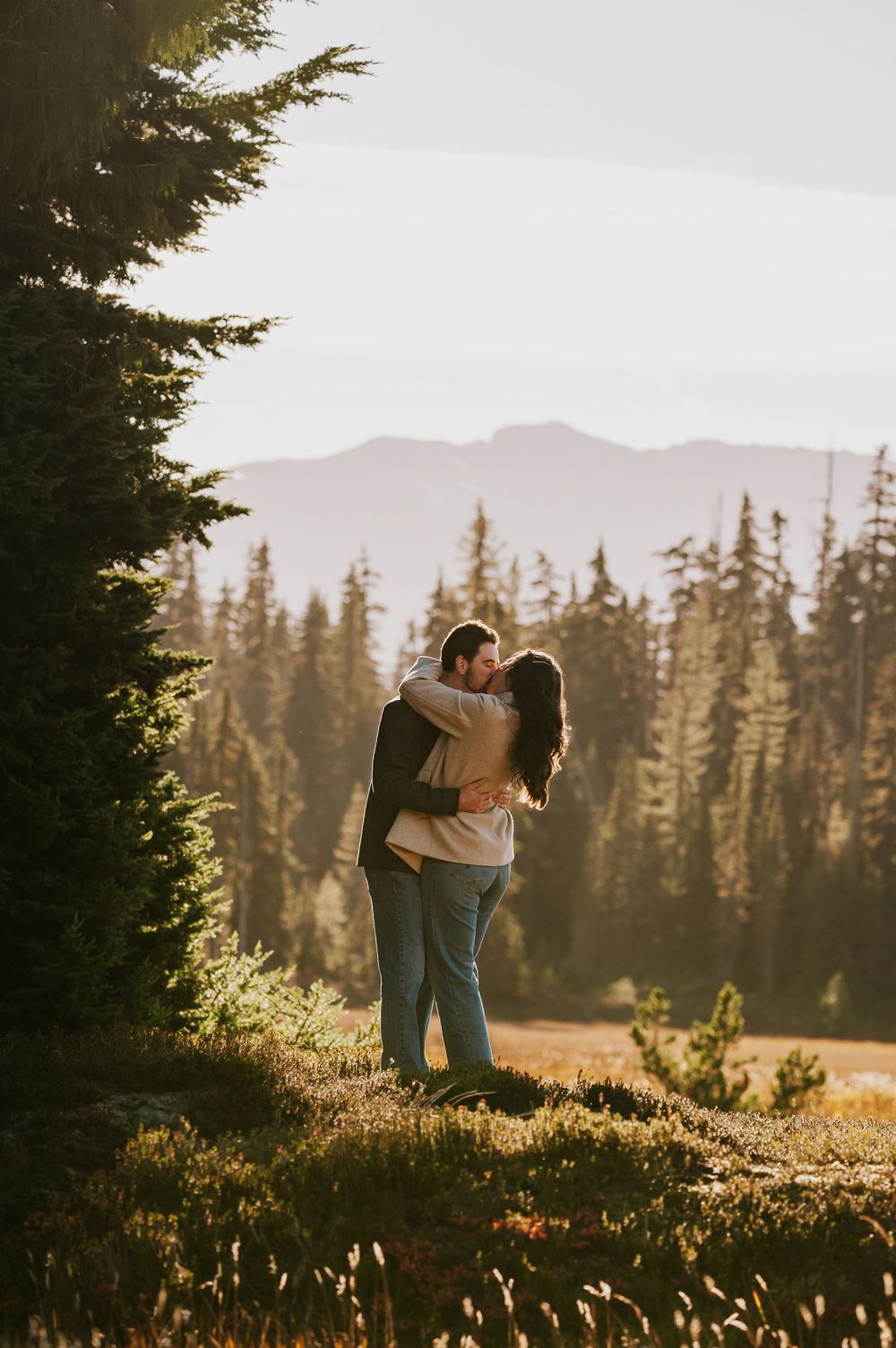 Engagement photographer of couple on Mt. Washington kissing in Paradise Meadows for couple photoshoot in front of mountains