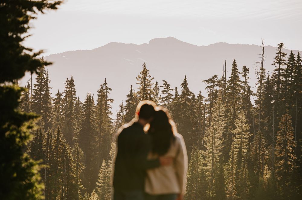 Engagement photographer of couple on Mt. Washington hugging in Paradise Meadows for couple photoshoot looking at mountains