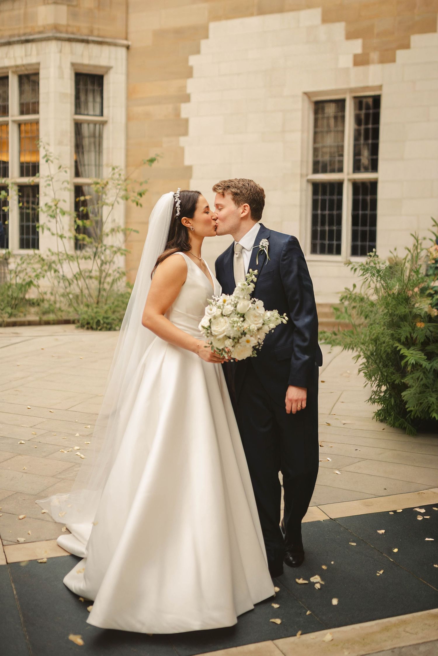 Wedding couple sharing intimate moments on stone patio with autumn leaves.