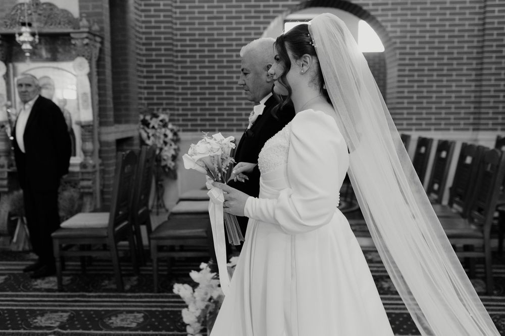 Black and white photo of a wedding ceremony inside a traditional church with brick walls.