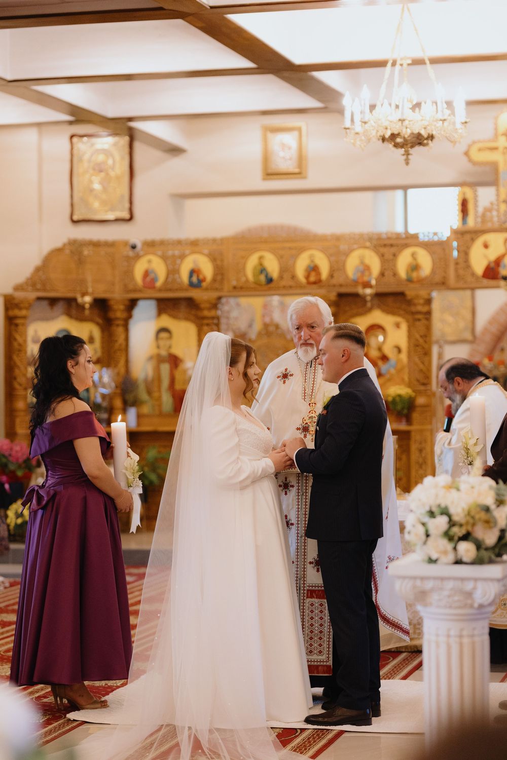 Traditional church wedding ceremony with bridesmaids in purple dresses and bride in white gown.