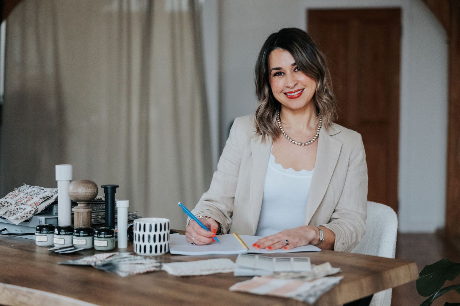 Professional sitting at desk with laptop and papers while taking notes in a bright modern office setting.
