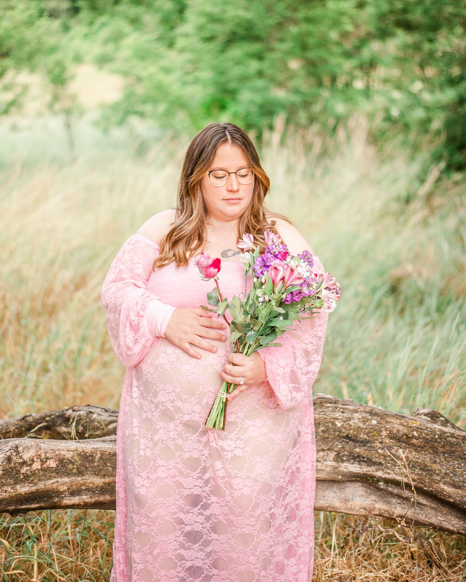 A figure in a pink lace dress gathers wildflowers in a sunlit meadow during a dreamy outdoor photoshoot.