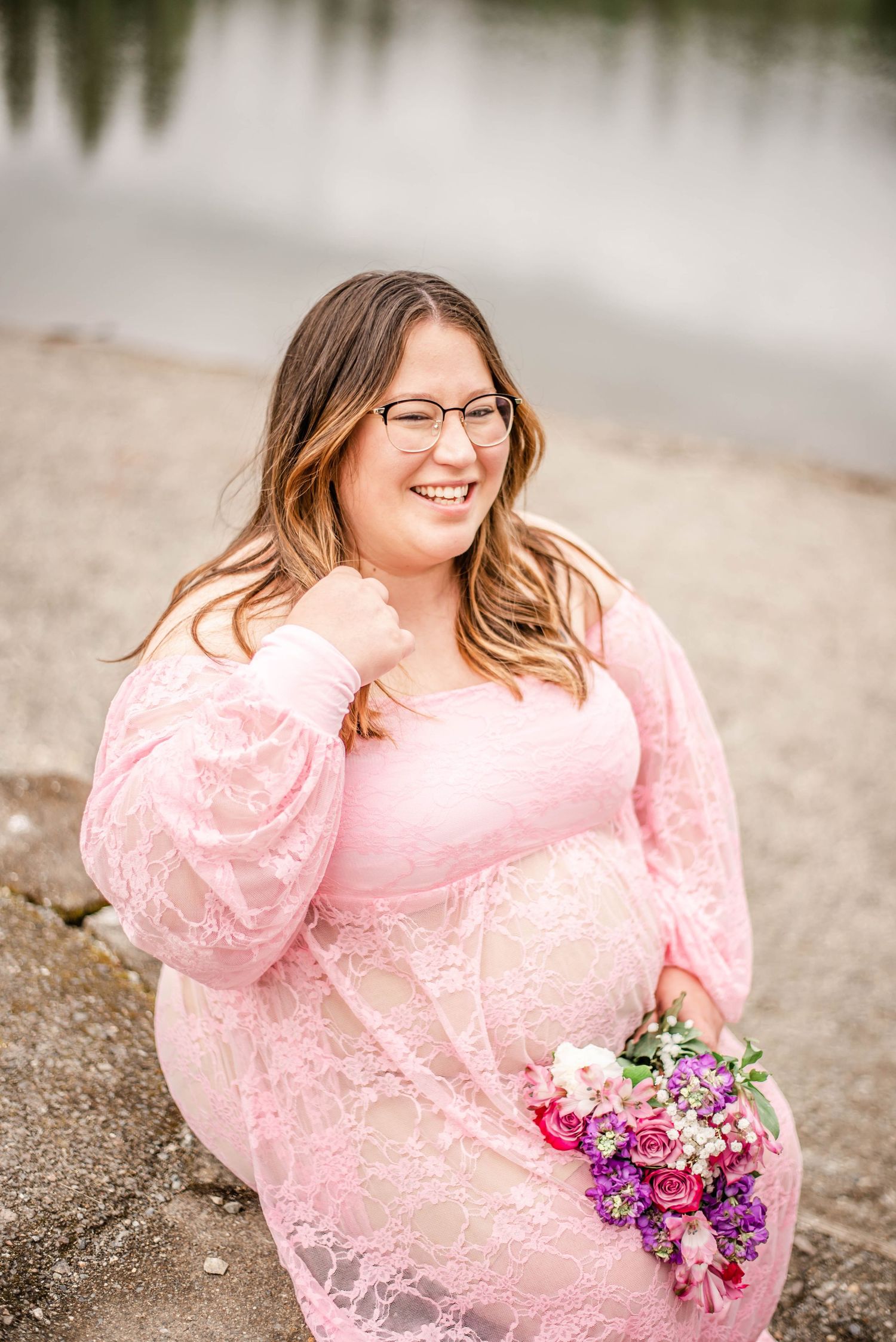 A beautiful pink lace dress with glasses and a colorful bouquet of flowers by a serene lake.