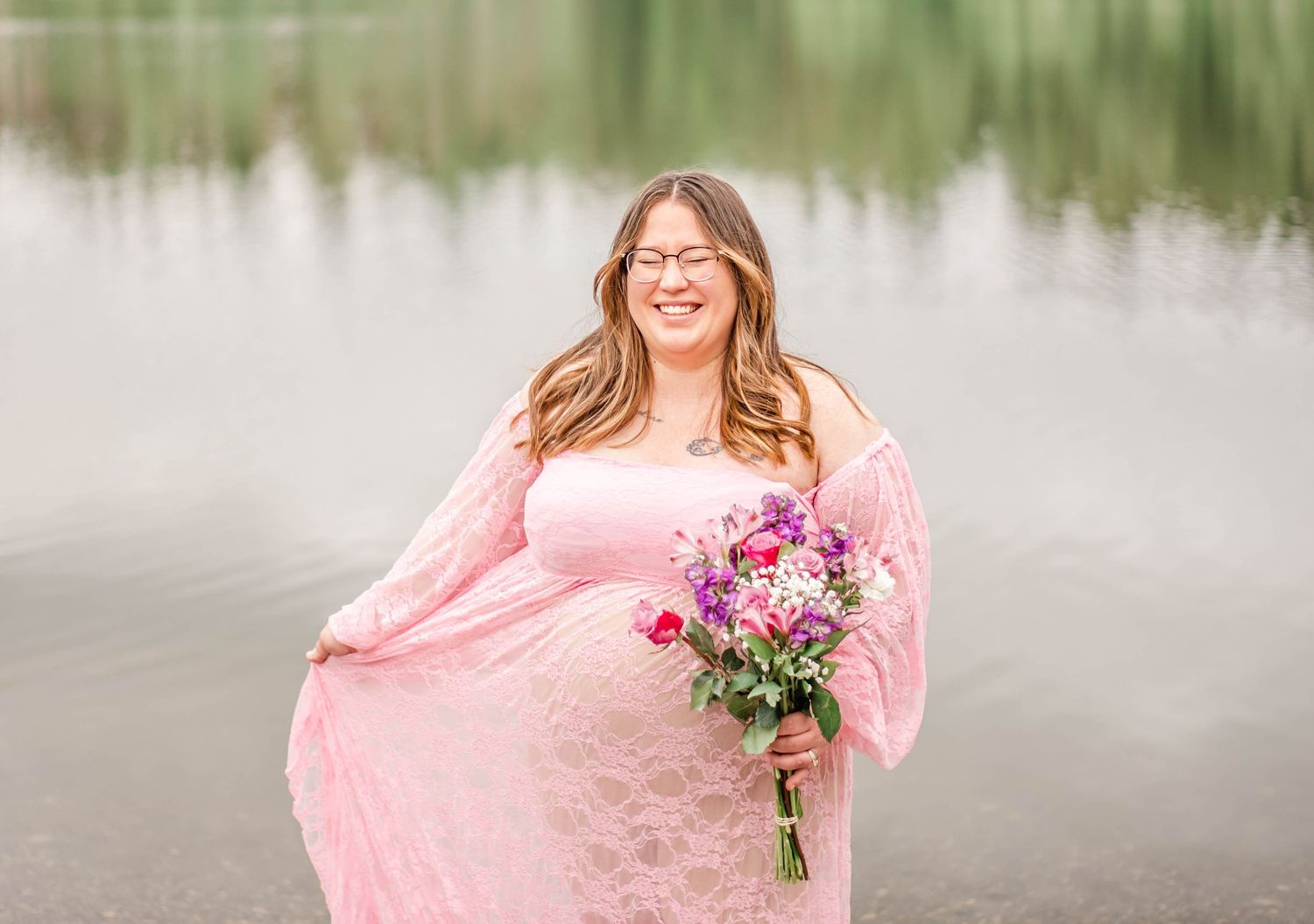Outdoor portraits in pink dress with floral bouquet by a serene lake with natural lighting.
