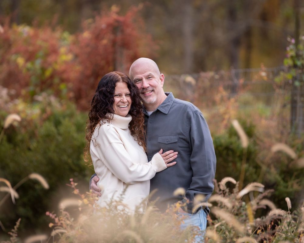 portrait of smiling couple embracing in an autumn meadow with colorful foliage in the background. middletown nj