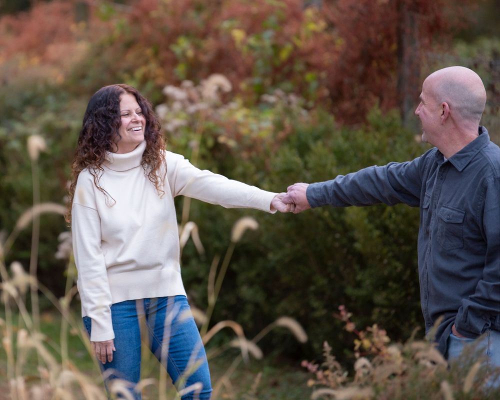 portrait of couple holding hands and smiling at each other in a scenic autumn outdoor setting.Poricy Park Middletown NJ Monnouth County