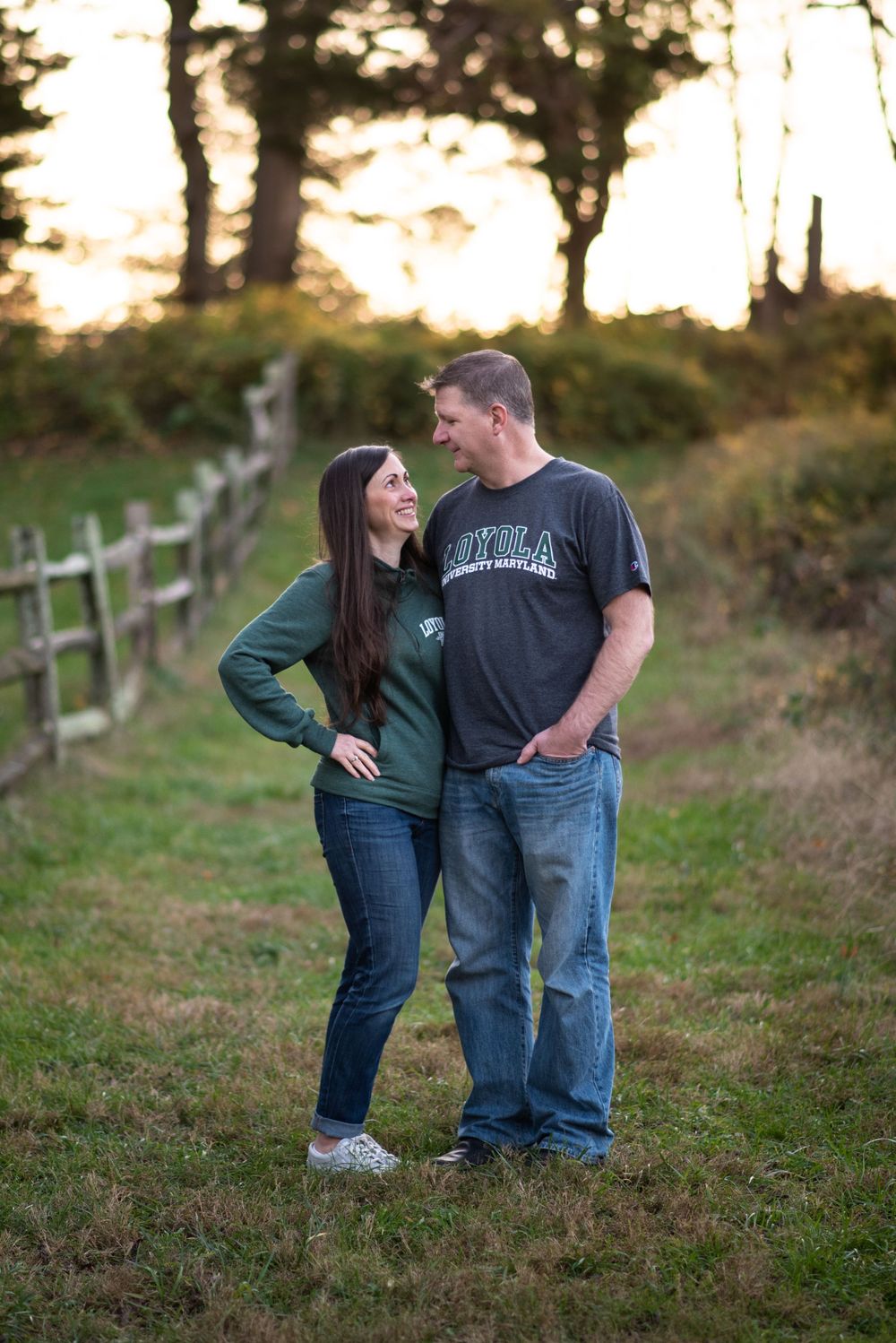 Casual couples portrait on hillside path with rustic fence at golden hour in Huber Woods Middletown NJ