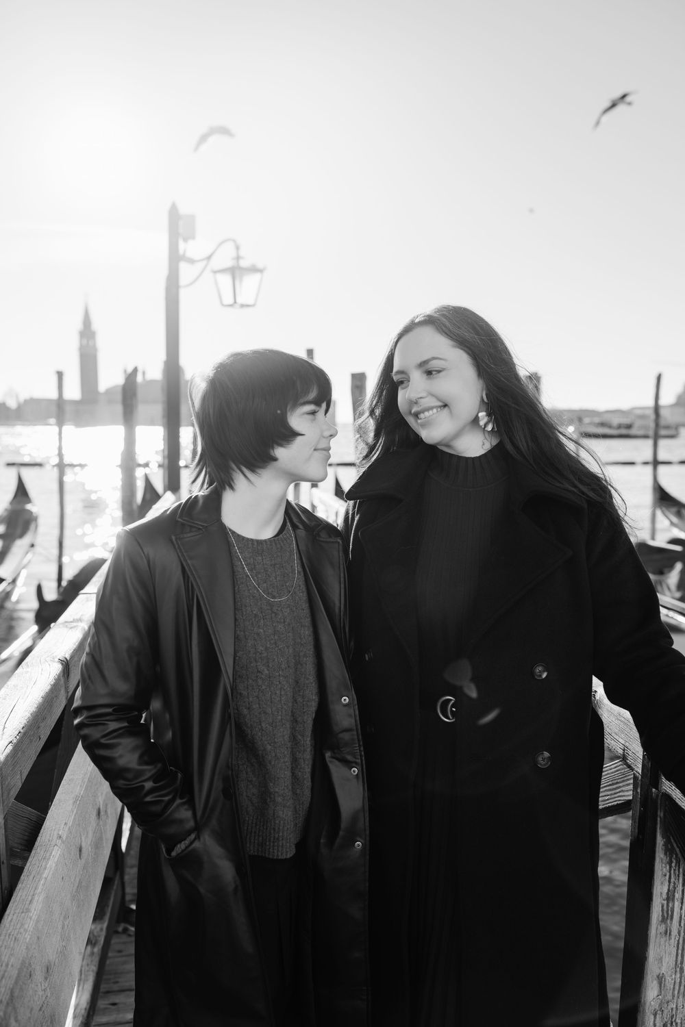 A couple shares intimate moments in black and white photos against a backdrop of Venice's canals and gondolas. Photographer for a family.