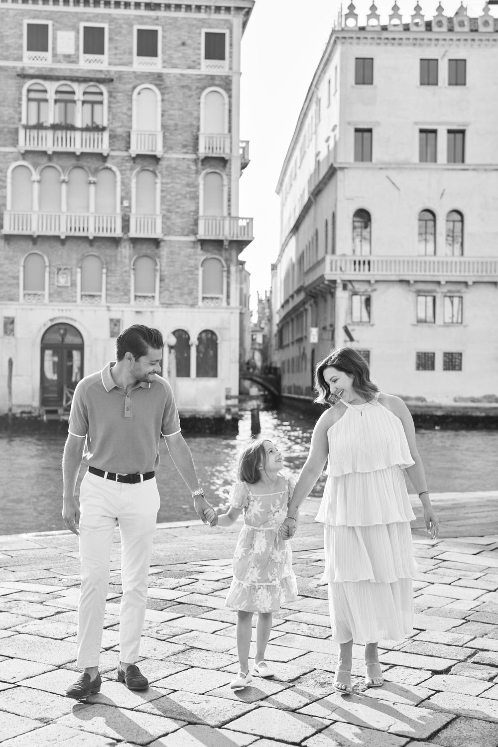 A black and white series of romantic couple photos walking and dancing in a historic European plaza.