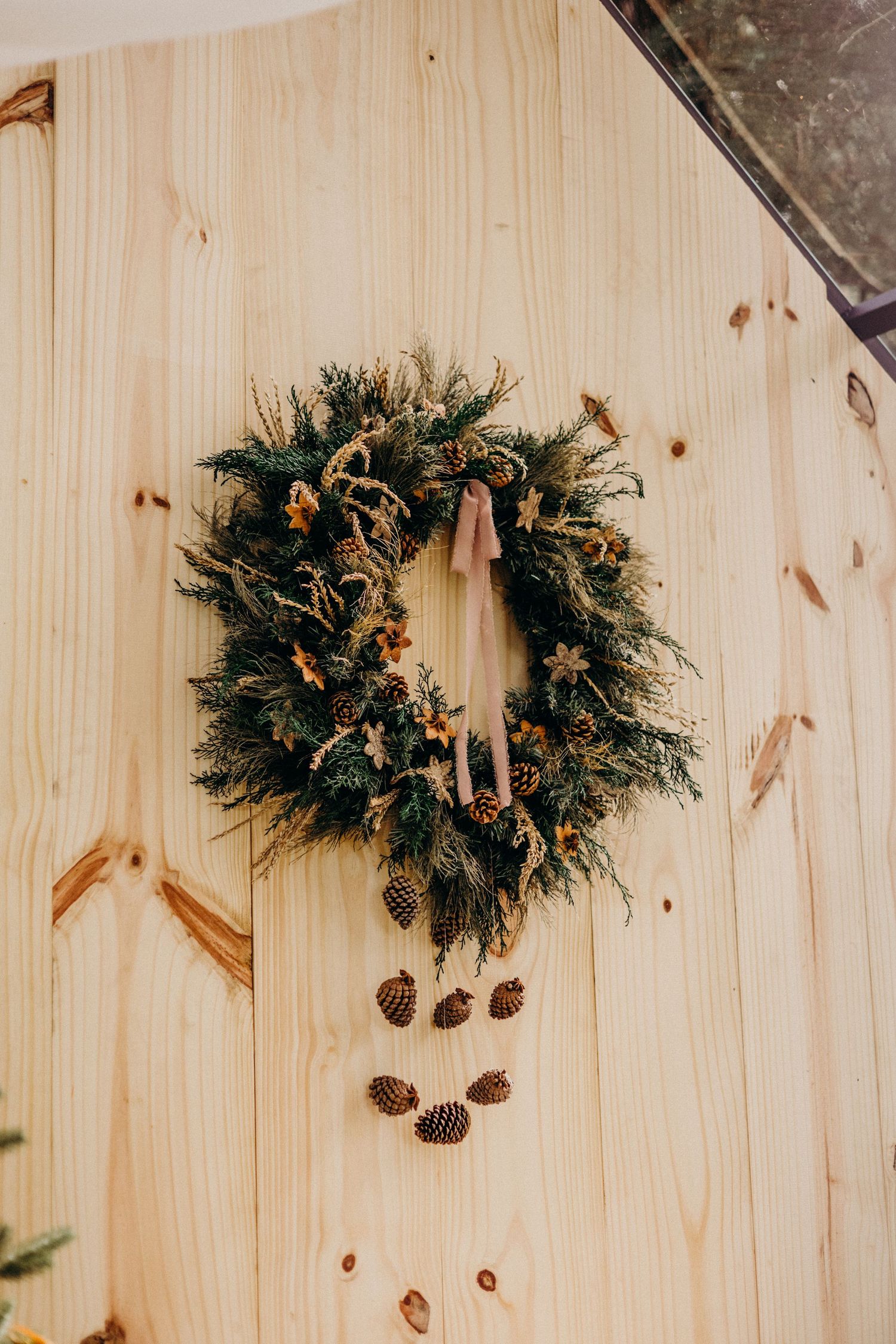 Studio family portrait with festive wreath decoration and white backdrop.