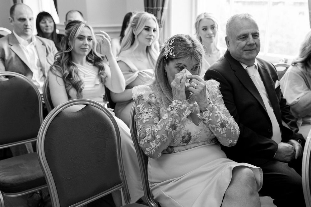 Black and white photo showing emotional wedding guests reacting during a ceremony.