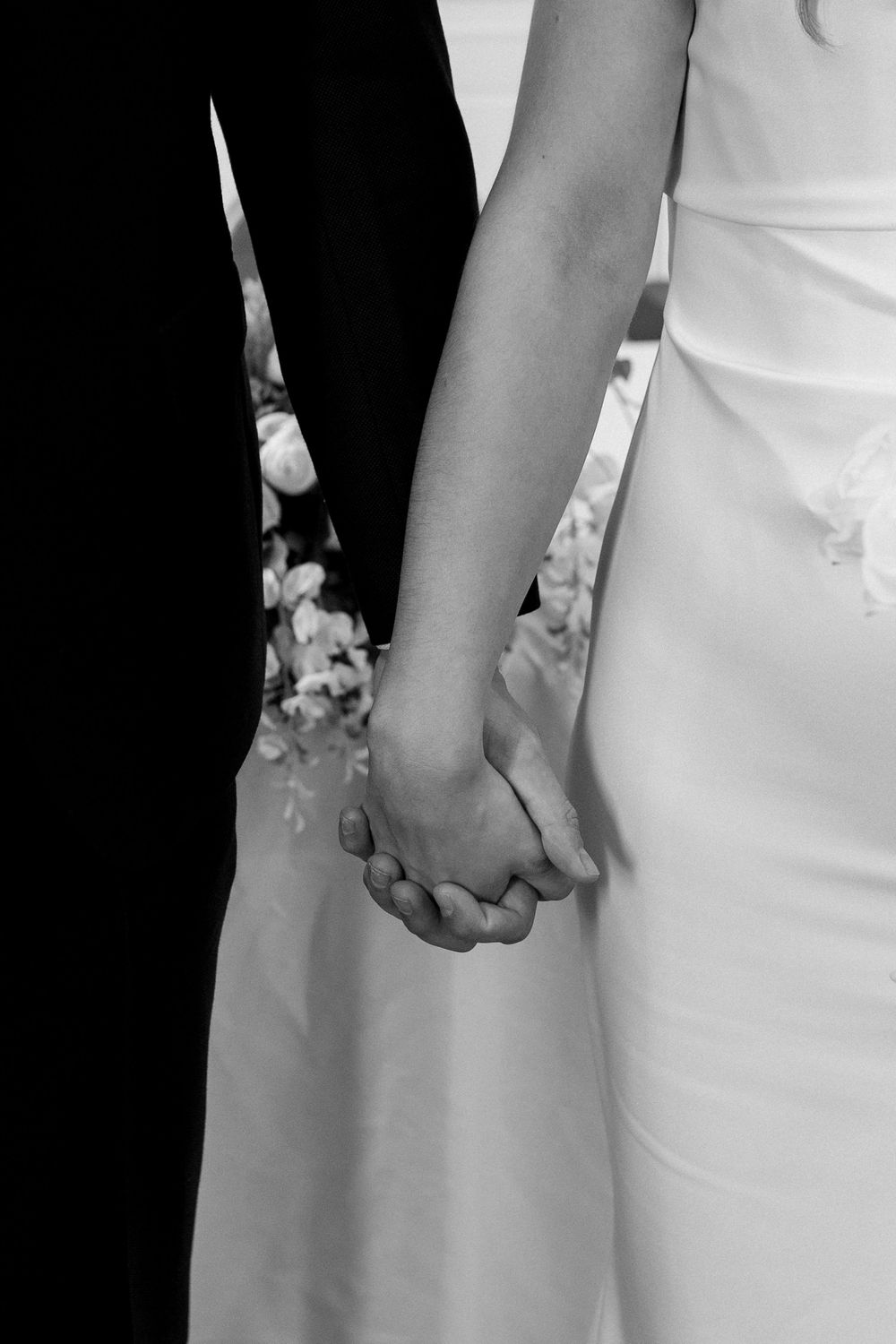 Close-up black and white detail of hands against formal clothing at an elegant event.