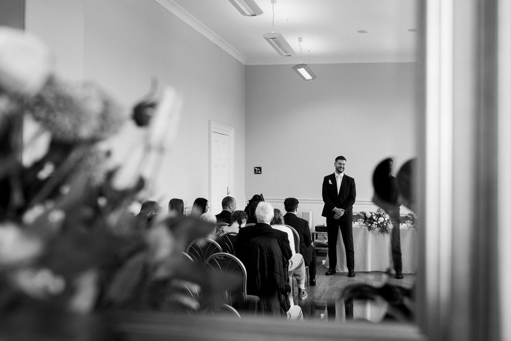Black and white panoramic view of a business meeting room with multiple attendees seated at tables.