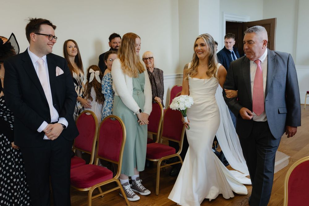 Wedding guests gather and socialize in a bright indoor venue during a celebration event.