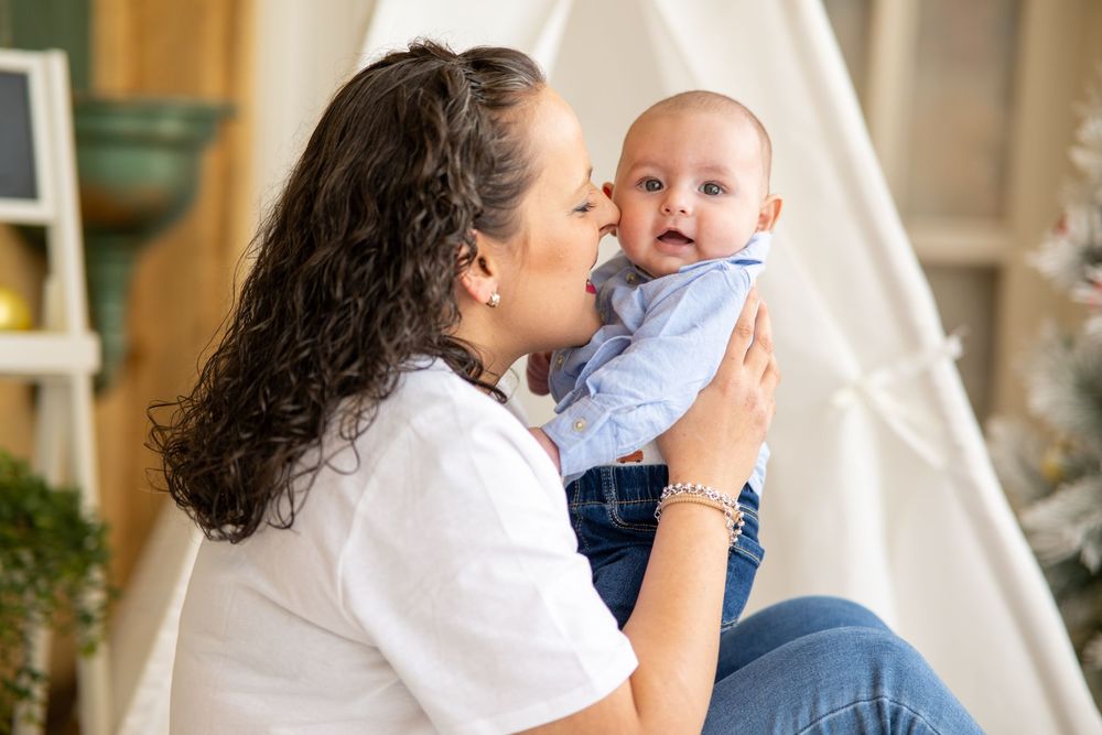 A tender moment between a parent and baby as they play and laugh together in a bright indoor setting.