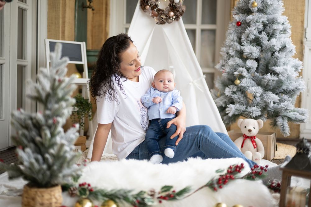 A festive Christmas scene with a decorated white teepee tent and flocked trees creating a cozy winter wonderland setting.