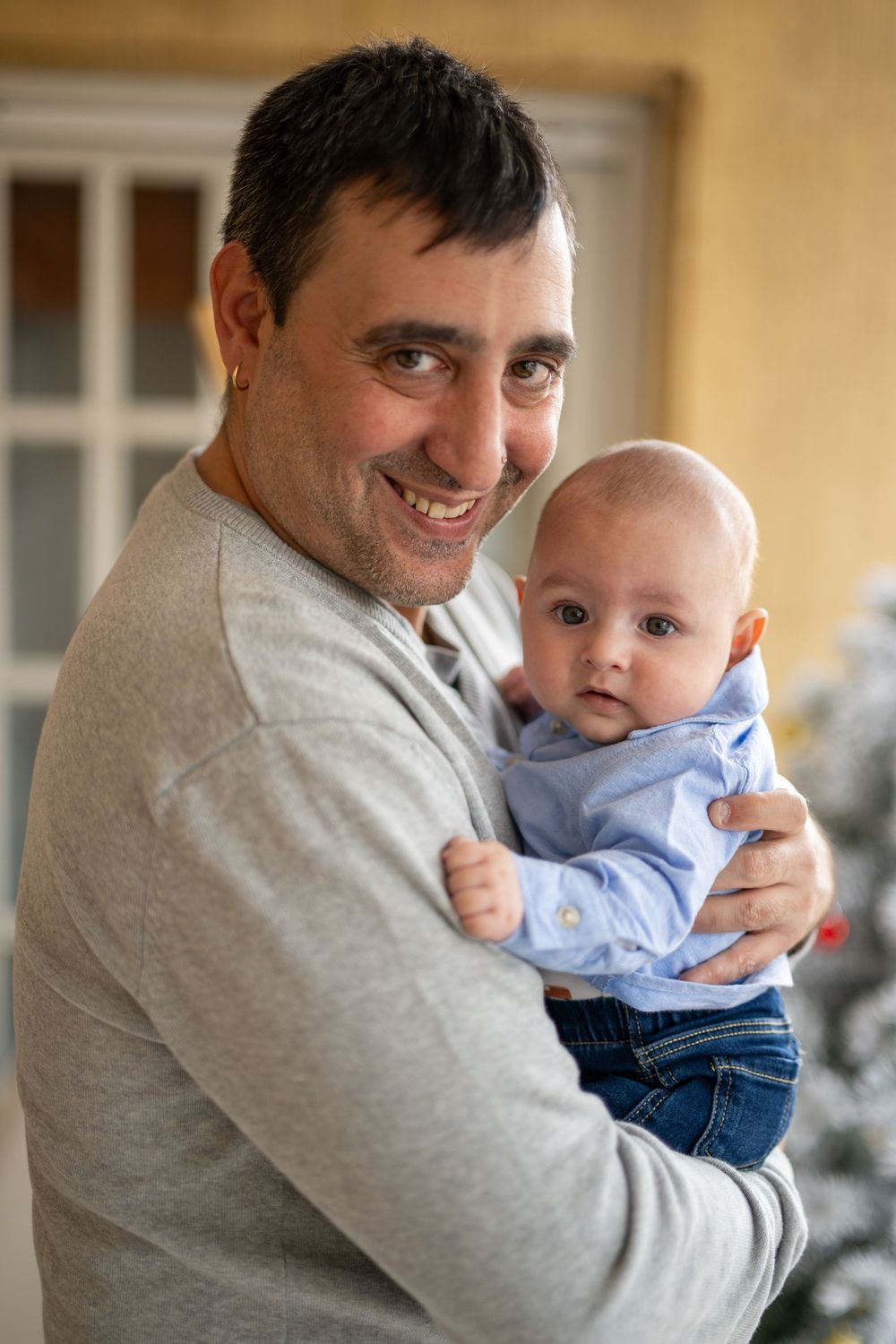 Parent in gray sweater holding and playing with smiling baby wearing blue outfit in series of candid moments.