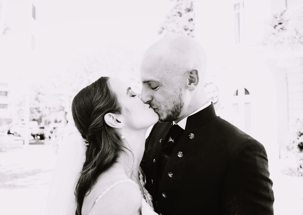 A black and white collage showing four romantic moments of a couple sharing tender kisses.