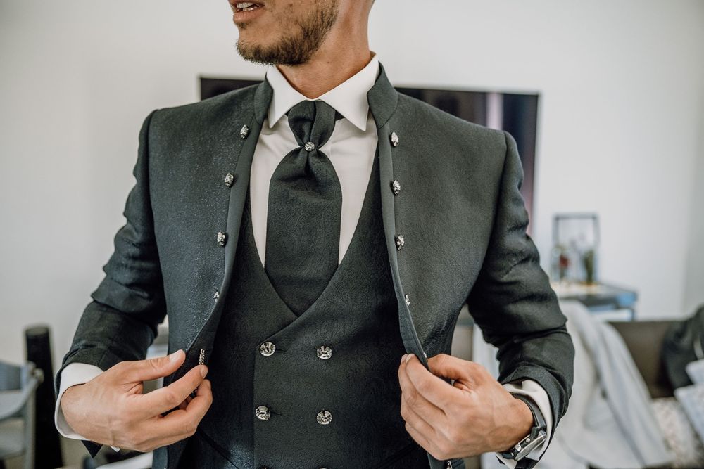 A close-up view of a dark green suit jacket with matching tie and white dress shirt.
