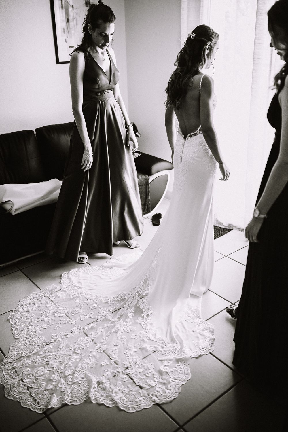 A black and white photo series showing the elegant lace train of a wedding dress against light colored floor tiles.